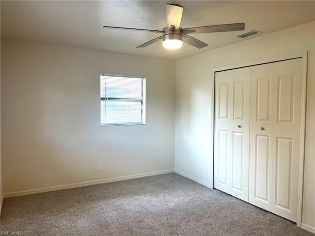 Unfurnished bedroom featuring light colored carpet, a closet, and a ceiling fan