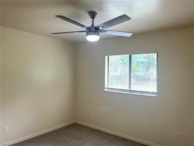 Carpeted spare room with baseboards and ceiling fan