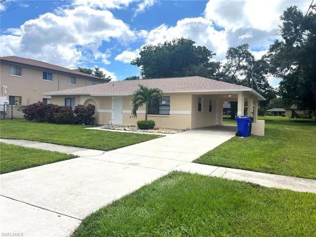View of front of house featuring a front lawn, stucco siding, concrete driveway, and an attached carport