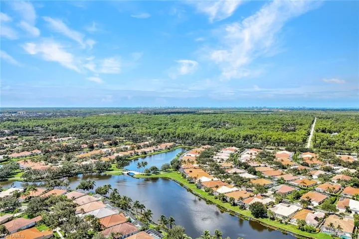 Residential community with a central waterway, lush green landscaping, and individual properties featuring tile roofs