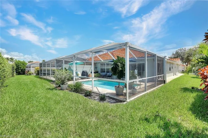 Expansive screened lanai featuring an in-ground swimming pool, terracotta roof tiles, and manicured landscaping