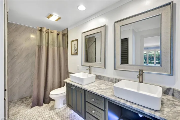 Double vanity with rectangular vessel sinks, framed mirrors, and a stone countertop