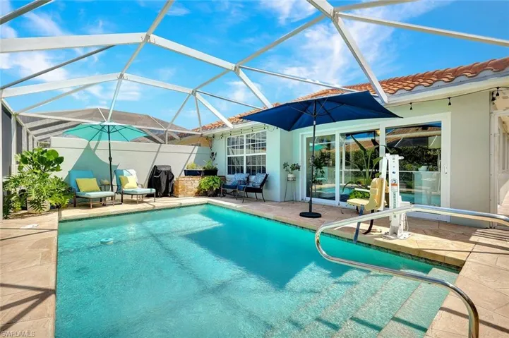 Screened outdoor pool area featuring a tile roof, sliding glass doors, and a pool handrail