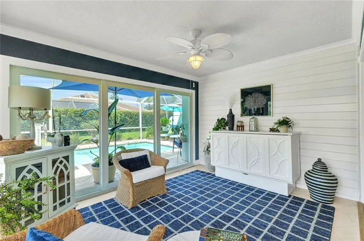 Sliding glass doors, shiplap wall, ceiling fan, crown molding, and tiled flooring