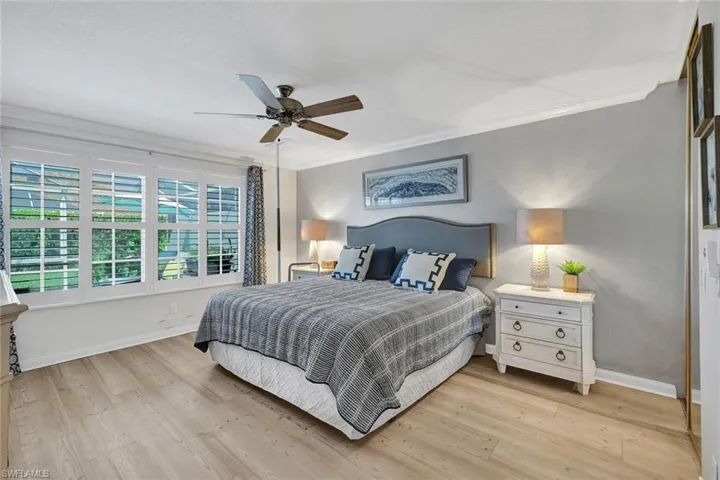 Wood-finish flooring, crown molding, and multiple windows with plantation shutters