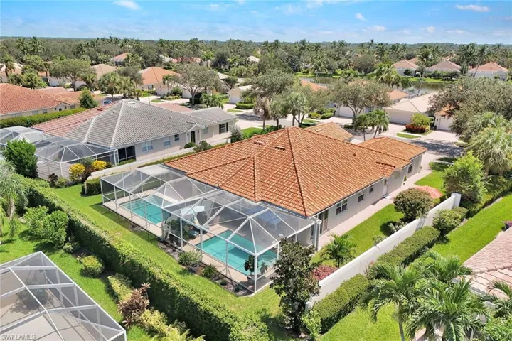Spacious property featuring a screened-in swimming pool, mature landscaping, and a red tile roof