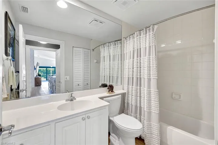 Bathroom featuring a single vanity with an integrated sink, white cabinetry, and a full-width mirror