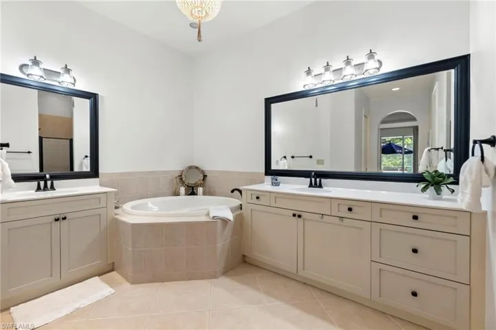 Bathroom featuring a garden tub, two vanities, a sink, and tile patterned floors