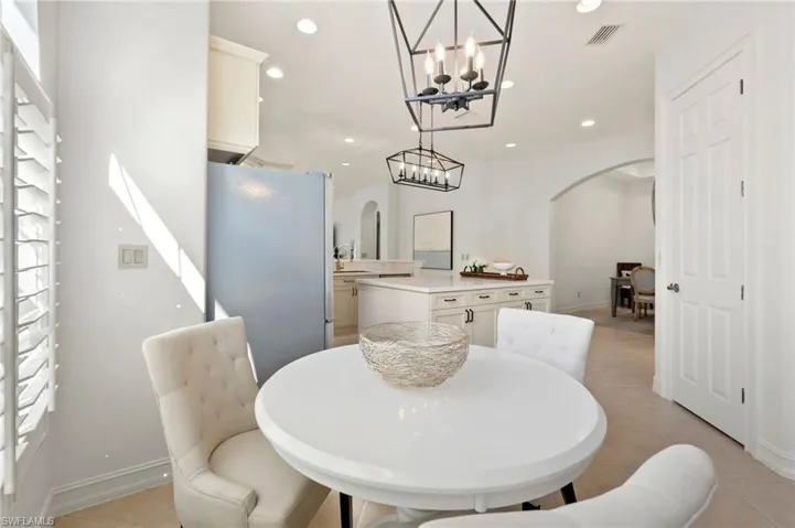 Dining room featuring arched walkways, light tile patterned floors, recessed lighting, visible vents, and baseboards