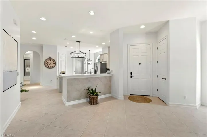 Entryway with recessed lighting, arched walkways, baseboards, and light tile patterned floors