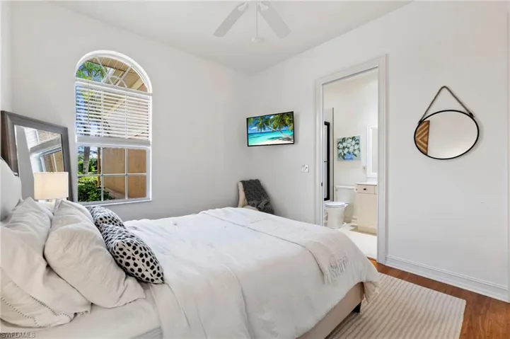 Bedroom with a ceiling fan, ensuite bathroom, baseboards, and wood finished floors