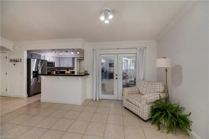 Kitchen with crown molding, white cabinets, light tile flooring, and appliances with stainless steel finishes