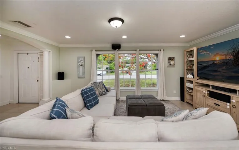 Tiled living room with ornamental molding and decorative columns