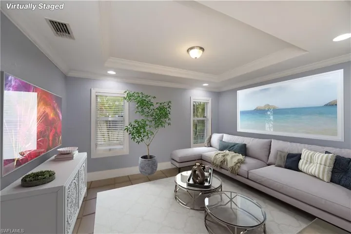 Tiled family room featuring a tray ceiling and crown molding