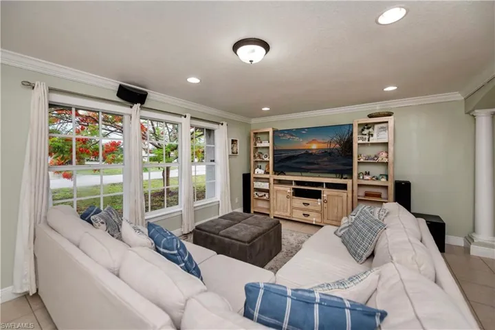 Living room with ornamental molding, decorative columns, and light tile floors