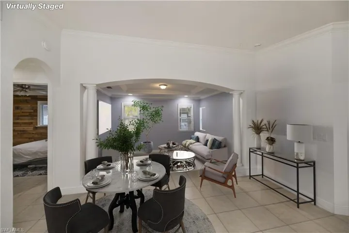Dining space featuring ornate columns, ceiling fan, a raised ceiling, and crown molding