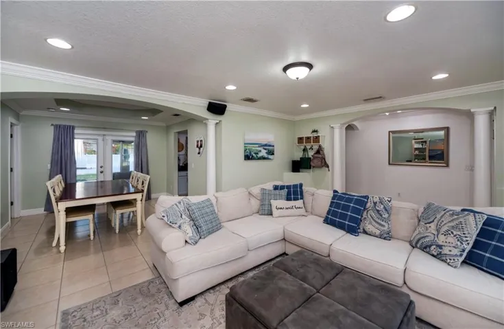 Living room featuring french doors, crown molding, and decorative columns
