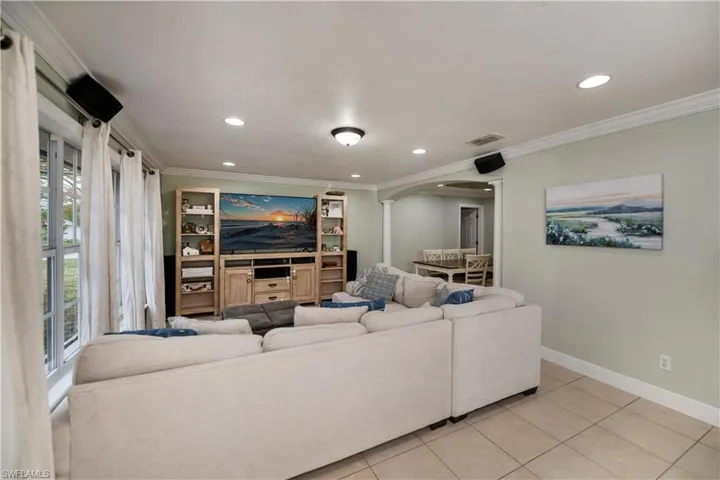 Living room with ornamental molding and light tile floors