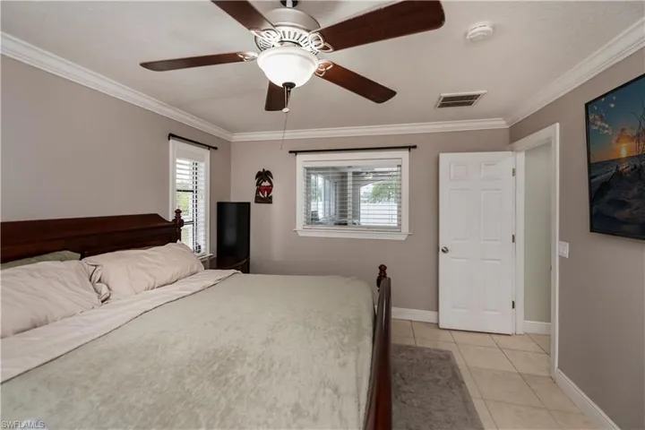 Unfurnished bedroom with crown molding, ceiling fan, and light tile floors