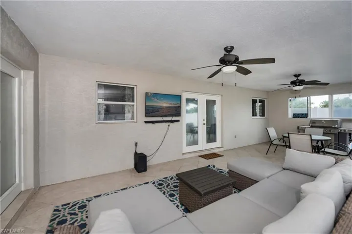 Tiled living room with a textured ceiling, ceiling fan, and french doors