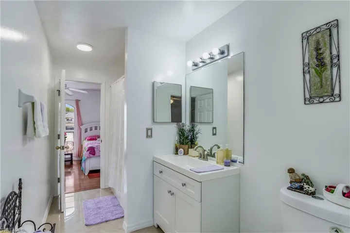 Full bathroom featuring vanity, toilet, tile patterned floors, and a ceiling fan