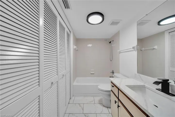 Guest Bathroom with closet washer and dryer, tile floor, Granite Counter, and Bathtub / shower combination, New Lighting