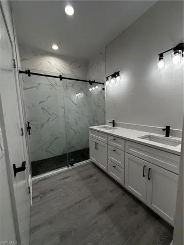 Bathroom with vanity, an enclosed shower, and wood-type flooring