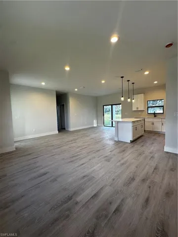 Kitchen with light hardwood / wood-style flooring, white cabinetry, hanging light fixtures, and a kitchen island