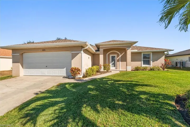 Single-story stucco residence featuring a two-car garage, arched entry, and a concrete driveway