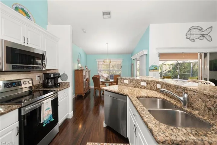 Kitchen featuring white cabinetry, stainless steel appliances, a double basin sink, and granite countertops