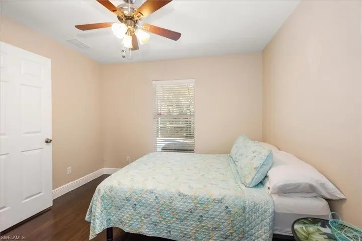 Room featuring wood-finish flooring, a ceiling fan with integrated lighting, and a single window with horizontal blinds