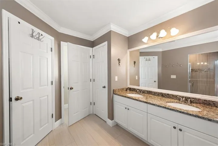 Bathroom featuring a dual vanity with a granite-style countertop, white cabinetry, and undermount sinks