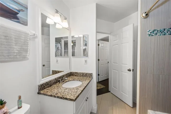 Bathroom featuring a white vanity with a speckled countertop, an undermount sink, and a large wall-mounted mirror
