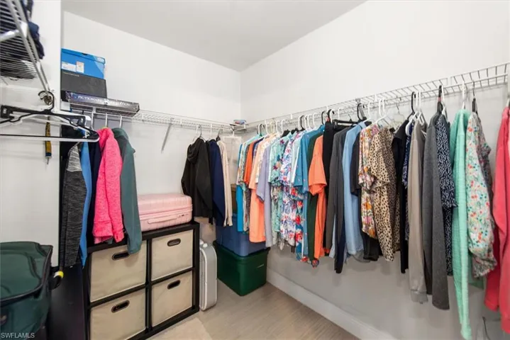 Walk-in closet featuring wire shelving, multiple hanging rods, and light-tone wood-finish flooring