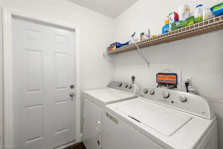 Dedicated laundry area featuring a white six-panel door, white walls, and built-in wire shelving