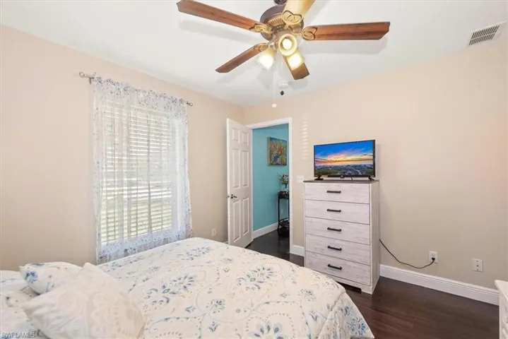 Bedroom featuring wood-finish flooring, a ceiling fan with integrated lighting, and a window with horizontal blinds