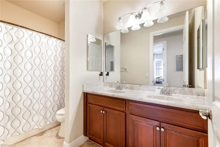 The guest bathroom offers dual sinks and a spacious shower-tub combination.