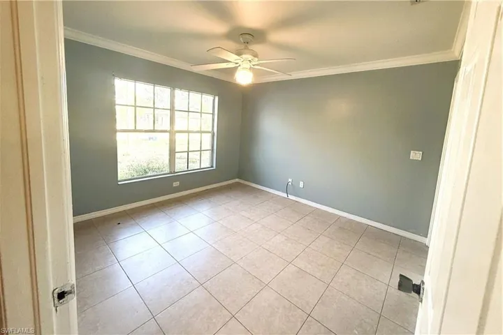 Spare room with crown molding, ceiling fan, and tile patterned floors