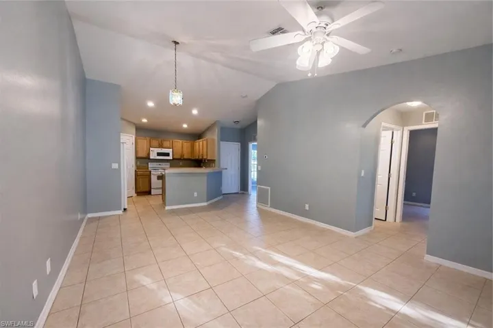 Unfurnished living room featuring a ceiling fan, light tile patterned floors, arched walkways, and recessed lighting