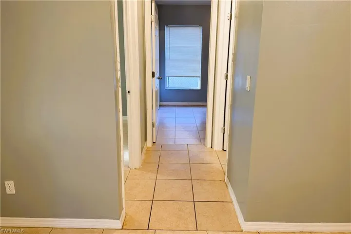 Hall with baseboards and light tile patterned floors