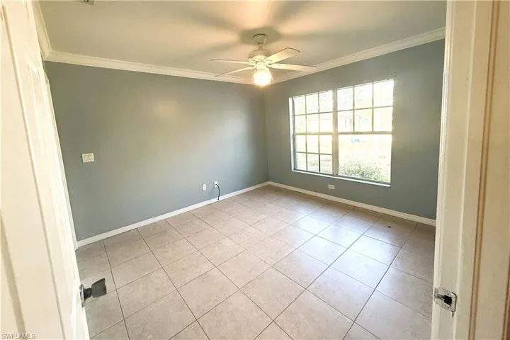 Tiled empty room with crown molding and ceiling fan