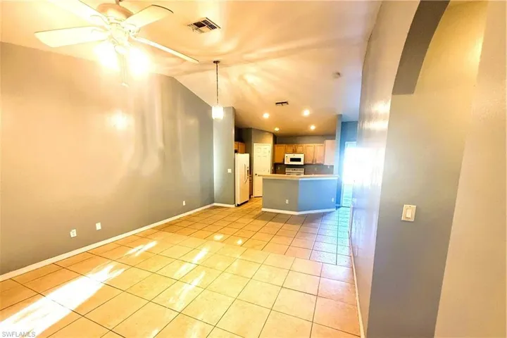 Unfurnished living room featuring vaulted ceiling, light tile patterned flooring, ceiling fan, recessed lighting, and arched walkways
