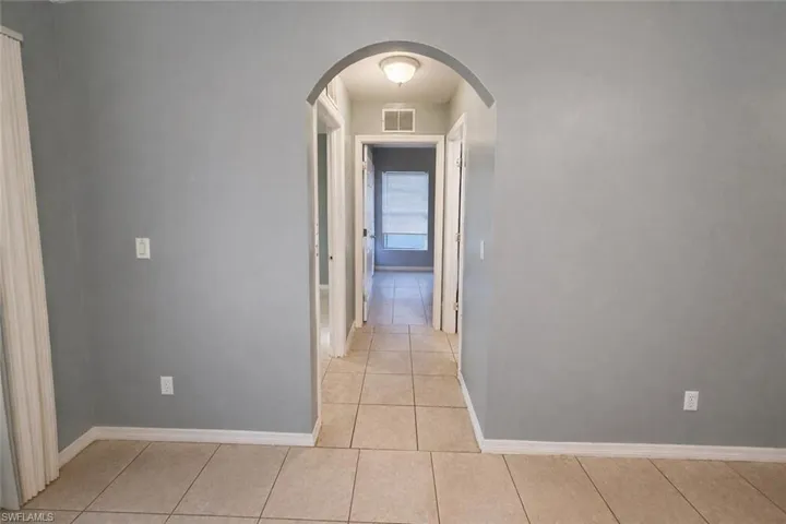 Corridor featuring arched walkways and light tile patterned flooring