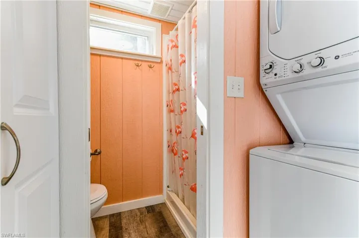Bathroom with a stall shower, stacked washer / dryer, and dark wood-type flooring