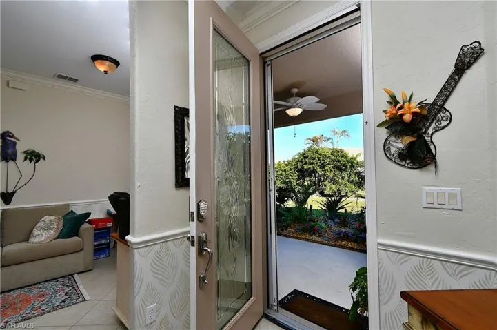 Doorway to outside featuring crown molding, ceiling fan, and light tile patterned floors