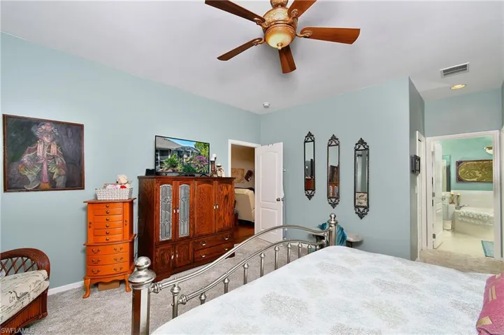 Bedroom with carpet floors, ceiling fan, and ensuite bathroom
