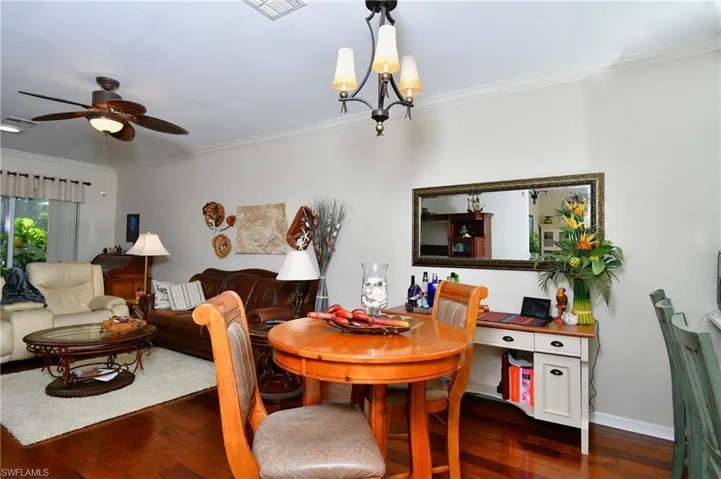 Dining space with crown molding, dark hardwood / wood-style floors, and ceiling fan with notable chandelier