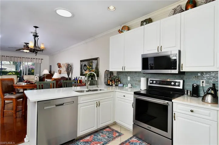 Kitchen featuring sink, white cabinets, hanging light fixtures, kitchen peninsula, and stainless steel appliances