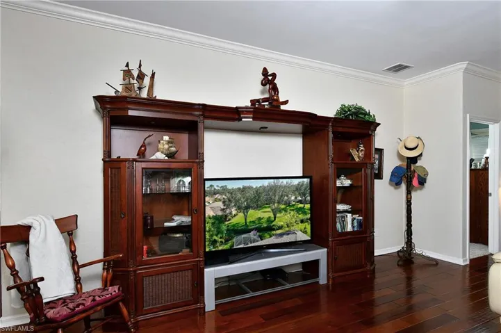 Living room with dark wood-type flooring and ornamental molding