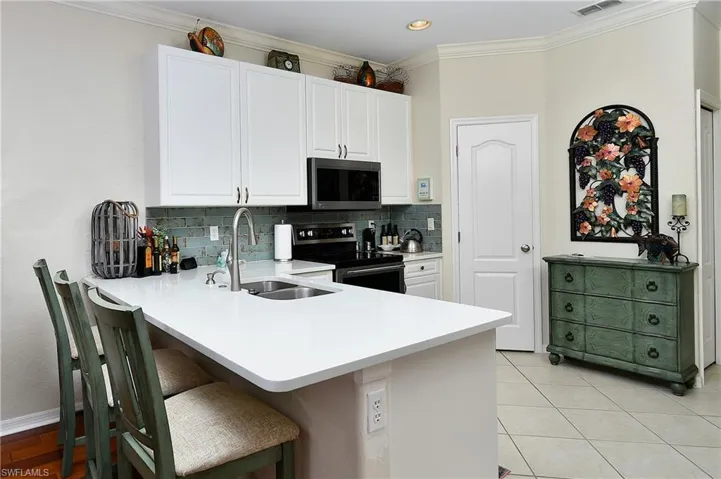 Kitchen with sink, a breakfast bar area, white cabinetry, kitchen peninsula, and stainless steel appliances